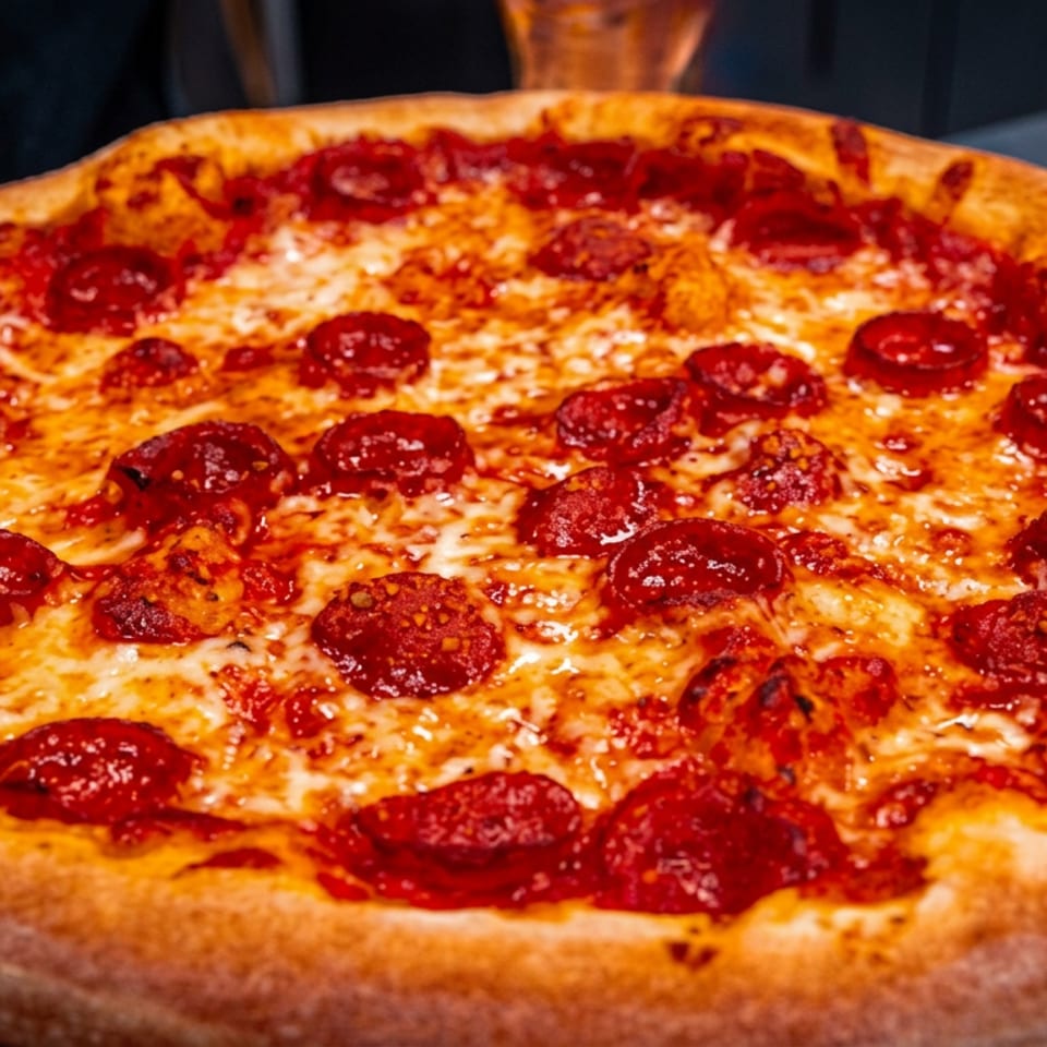 Pepperoni pizza with melted cheese and a golden-brown crust on a wooden serving board.
